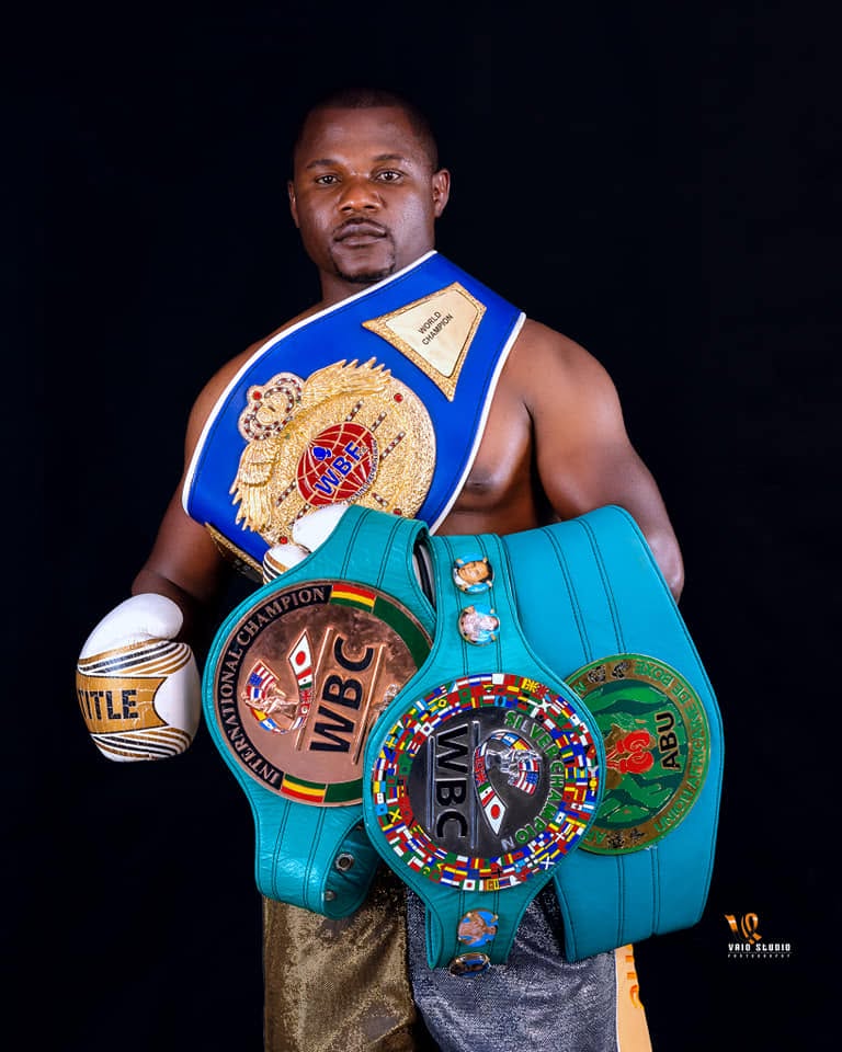 Charles Manyuchi standing with his championship belts