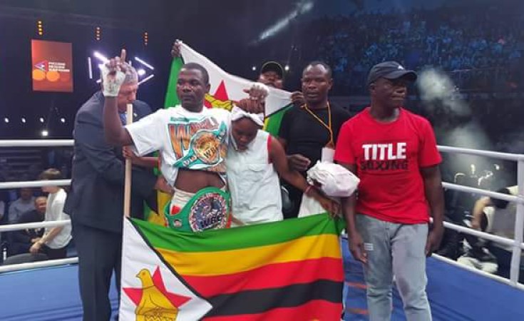 Charles Manyuchi celebrating in the ring wrapped in the Zimbabwean flag