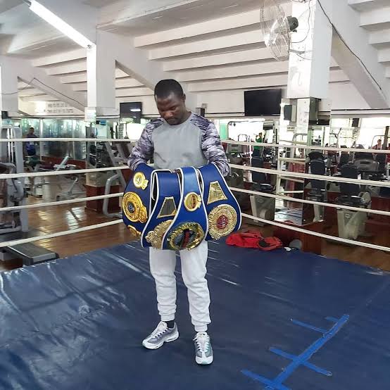 Charles Manyuchi holding a stack of belts in the gym